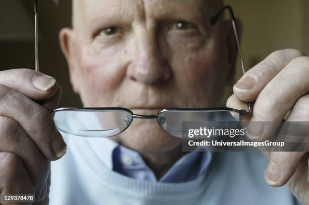 Elderly man putting on his glasses