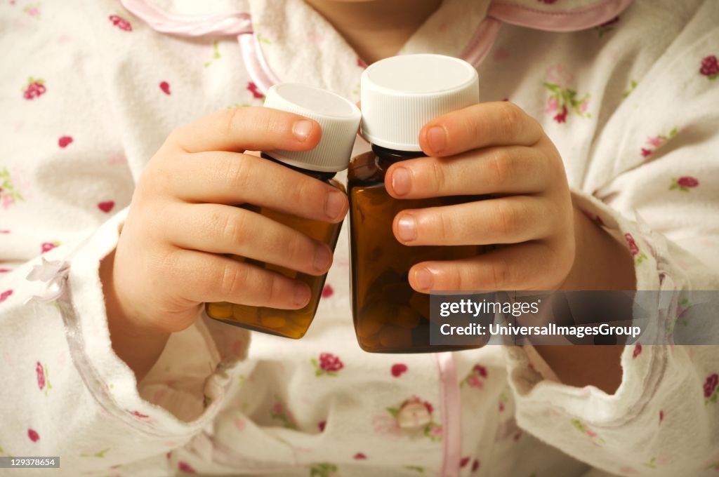 Close-up of baby girl playing with medicine bottles, mid section