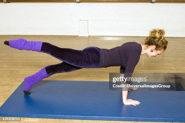 Woman in exercise class practicing Pilates leg pull front routine, An exercise class at the Body Control Centre in London in a Pilates Leg Pull Front...