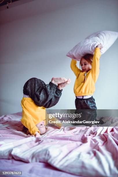 weibliche kinder mit kissen kampf im bett - kissenschlacht stock-fotos und bilder