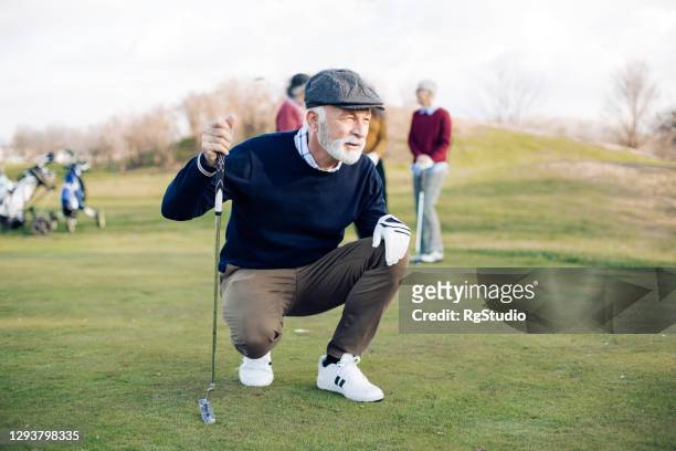 porträt eines älteren golfers, der einen schuss gemacht hat - golf stock-fotos und bilder