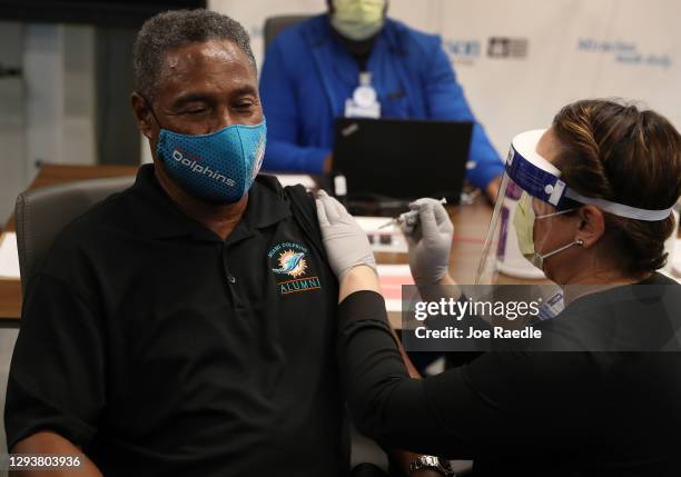 Nat Moore 69, former Miami Dolphin player, receives a Pfizer-BioNtech COVID-19 vaccine from Susana Flores Villamil, RN from Jackson Health System, at...