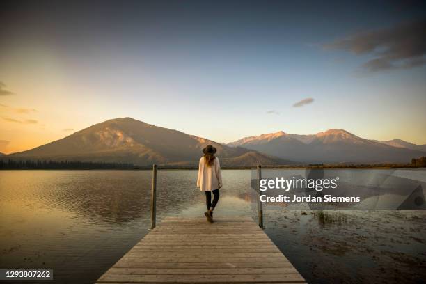a woman standing on a dock watching a scenic sunrise over vermillion lakes. - shoes top view stock pictures, royalty-free photos & images