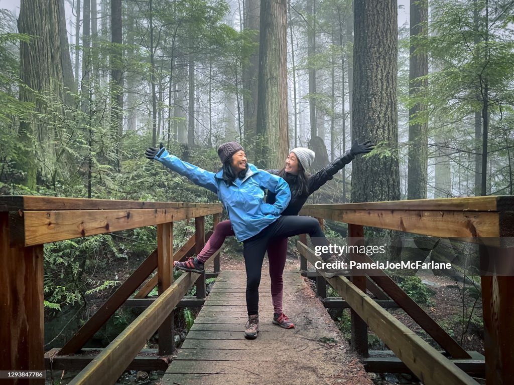 Asian Mother and Eurasian Daughter Posing on Bridge in Forest