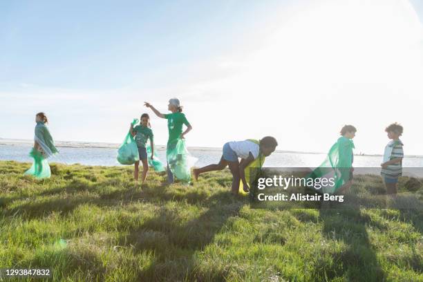 young green activists picking up litter in nature - aktivist stock-fotos und bilder