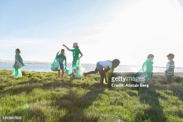 young green activists picking up litter in nature - plastic pollution beach stock pictures, royalty-free photos & images