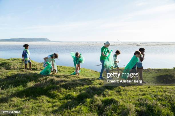 young green activists picking up litter in nature - summer super 8 stockfoto's en -beelden