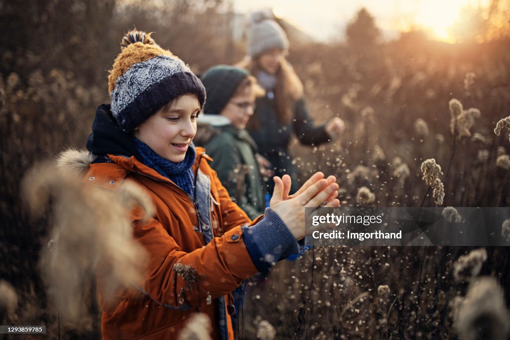 Children playing with dried grass on winter walk