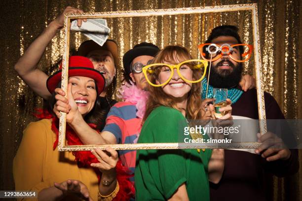 male and female friends taking funny photo in photo booth - holding prop stock pictures, royalty-free photos & images