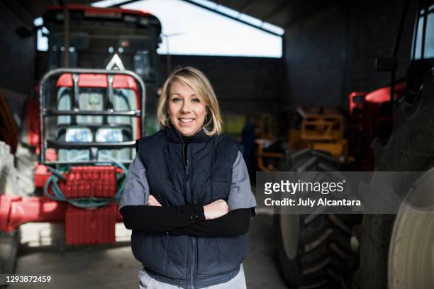 kvinna poserar på landsbygden traktorer lager. kvinna poserar på landsbygden traktorer lager. leende tittar på kameran - agricultural equipment bildbanksfoton och bilder