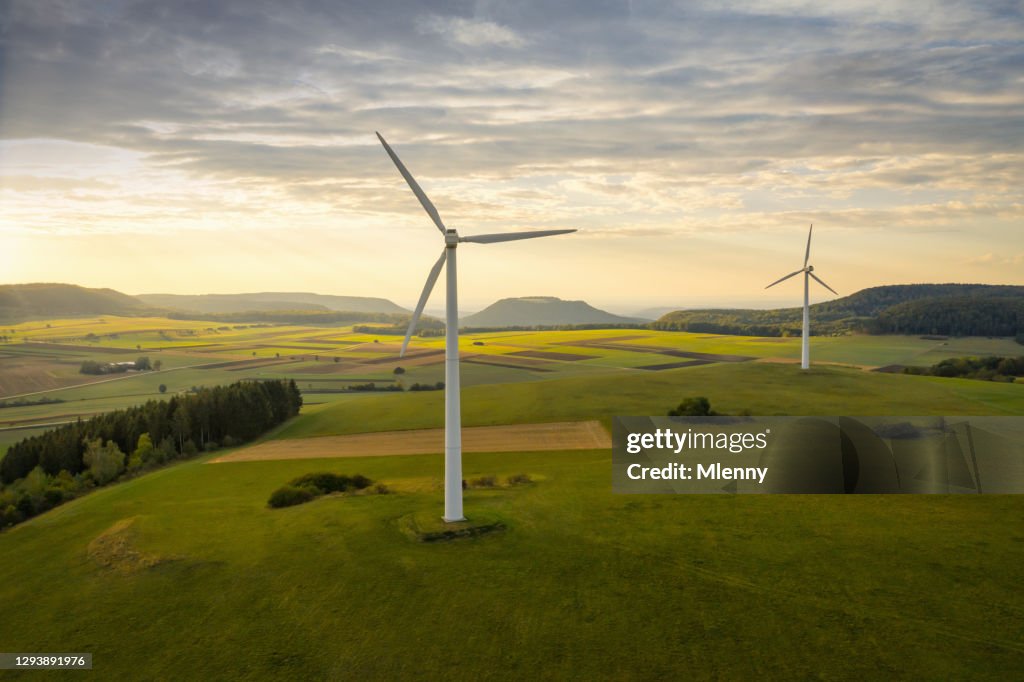 Alternative Energy Wind Turbine in Green Summer Landscape at Sunset