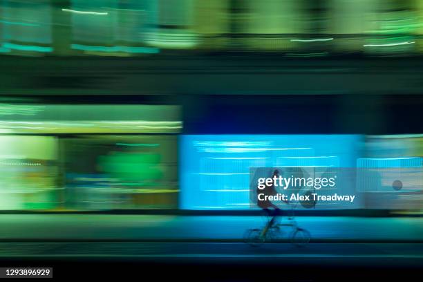 a cyclist on regent street in london cycling past illuminated shop windows - rush hour stock pictures, royalty-free photos & images