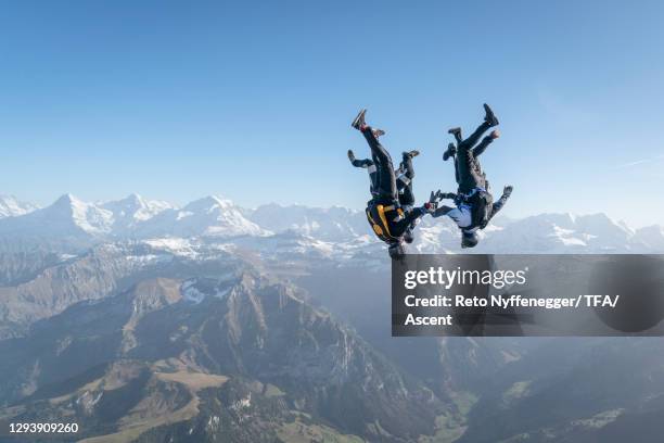 freefall jumpers in mid-air flight over mountains, valley - ville de berne photos et images de collection