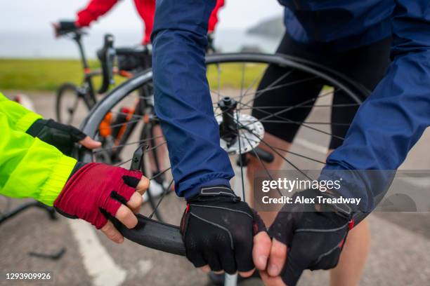 cyclists mend a puncture on a road bike while riding the north coast 500 route around scotland - rubber band stockfoto's en -beelden
