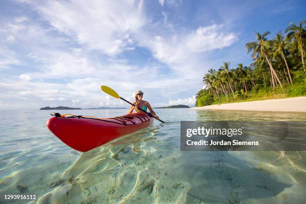 a woman paddling a canoe through the turquoise water of the philippines. - daily life in manila stock pictures, royalty-free photos & images