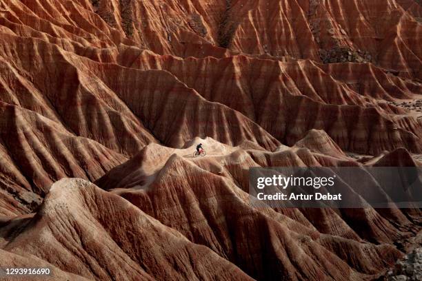 biker riding the rugged sandstone formations in the desert landscape of bardenas reales badlands in spain. montando en bicicleta en el paisaje desertico de las bardenas reales en el norte de españa con formaciones de tierra. - extreme sports bike stock pictures, royalty-free photos & images