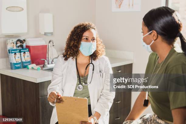 doctor and female soldier smile through protective masks - protective face mask stock pictures, royalty-free photos & images