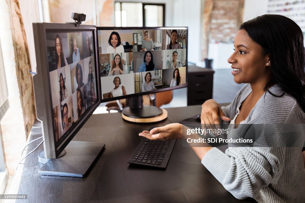 During COVID-19, attractive woman gestures during virtual meeting with colleagues
