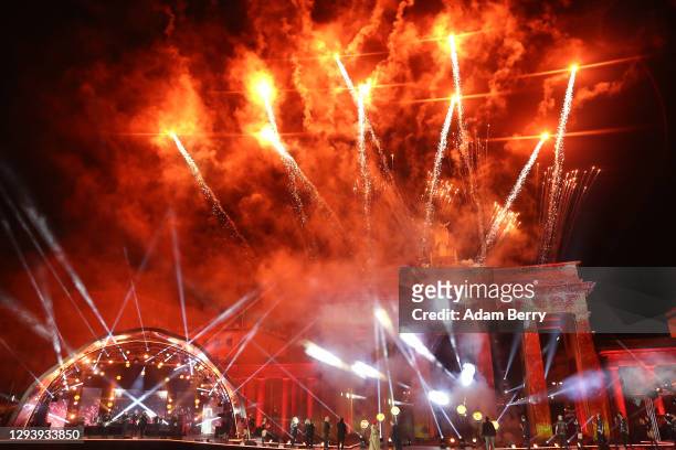 Fireworks explode at midnight, celebrating the official start of the new year during the "Willkommen 2021" performance behind the Brandenburg Gate on...