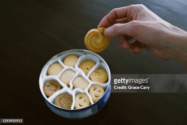 man selects butter cookie from container - danish pastry stock pictures, royalty-free photos & images