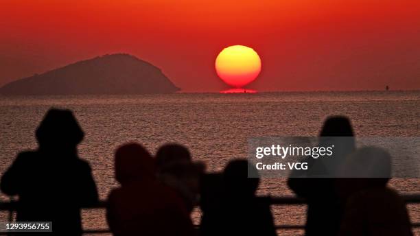 People watch the sunrise on New Year's Day at a beach on January 1, 2021 in Dalian, Liaoning Province of China.