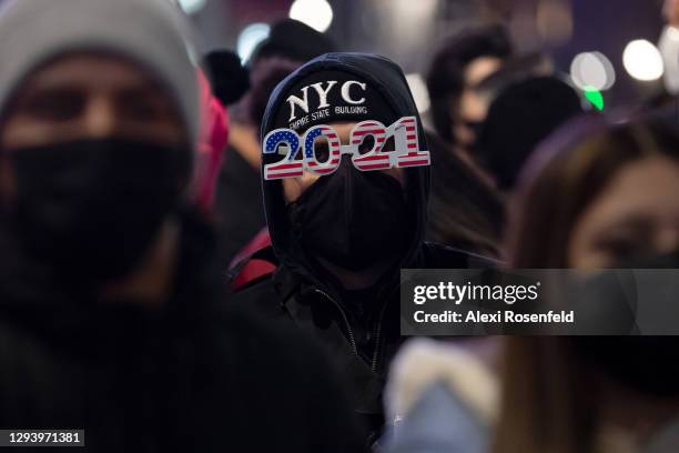 Woman wearing '2021' glasses stands in a crowd of people during the 2021 New Year’s Eve celebration in Times Square on December 31, 2020 in New York...