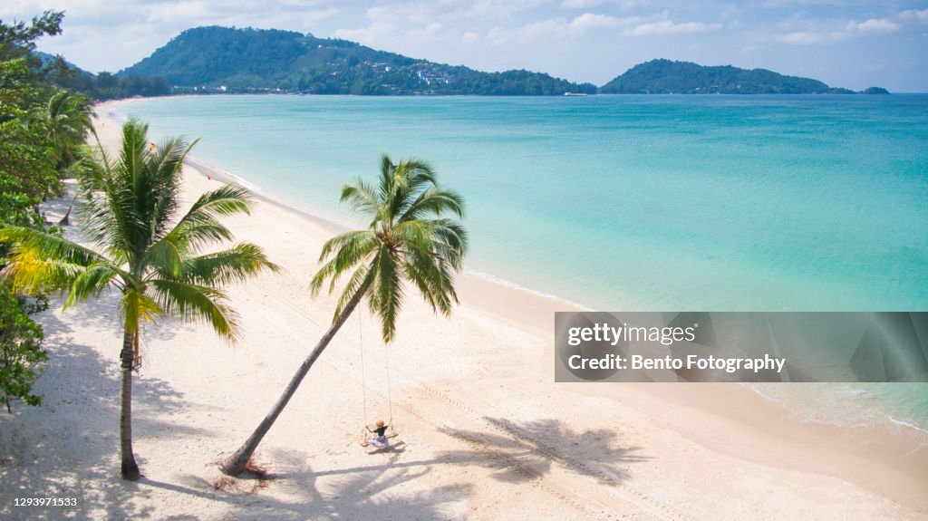 Solo traveller play on coconut swing in Patong beach, Phuket, Thailand.