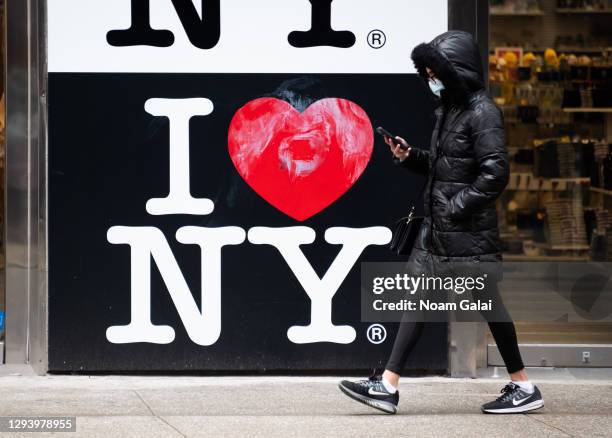 Person walks by an 'I love New York' sign in Times Square on December 31, 2020 in New York City. The pandemic has caused long-term repercussions...