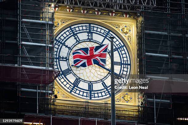 Union flag flies in front of the clock face of Elizabeth Tower, commonly known as Big Ben, just after the sun rises on January 01, 2021 in London,...
