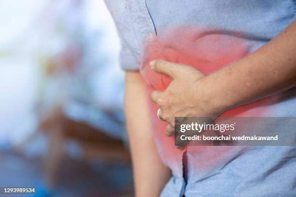 young man having stomach ache, painful area highlighted in red - human intestine stock-fotos und bilder