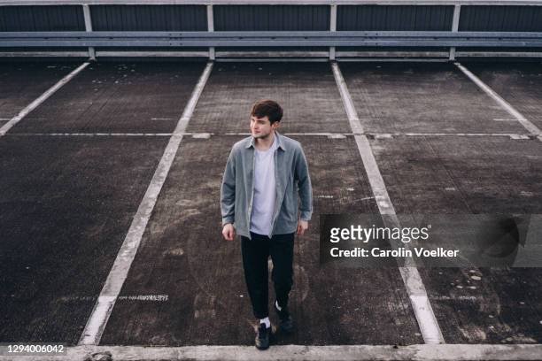 high angle view of young man walking on a parking lot - lot of people fotografías e imágenes de stock