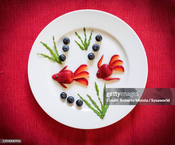 fishes made of strawberries and blueberries fruit in plate - food art stock pictures, royalty-free photos & images