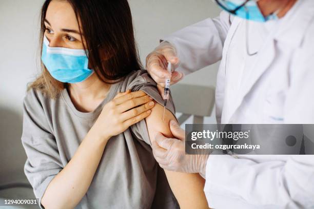 jonge vrouwen die coronavirusvaccin ontvangen - covid 19 vaccin stockfoto's en -beelden
