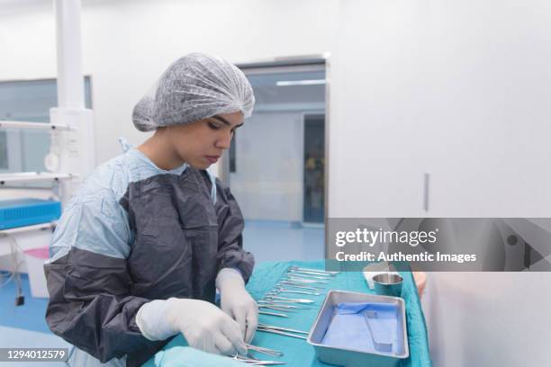 young latino female surgical technologist organizing medical instruments at operating room - equipamento cirúrgico imagens e fotografias de stock