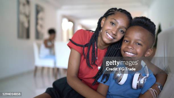 portrait of siblings embracing at home - sibling stock pictures, royalty-free photos & images