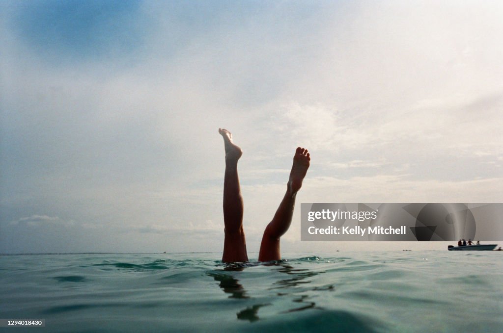 Swimmer legs in the sea at sunset
