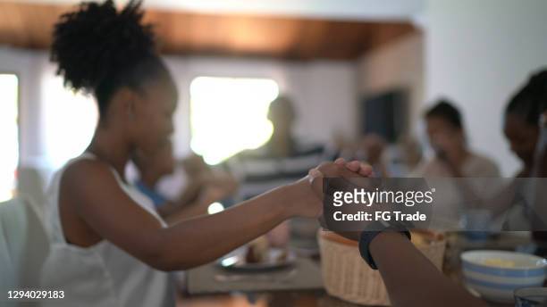 family saying grace over food at home - black woman praying stock pictures, royalty-free photos & images