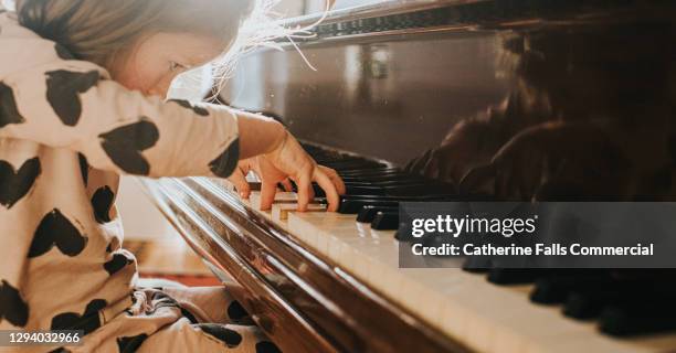 little girl playing a grand piano - child prodigy stock pictures, royalty-free photos & images