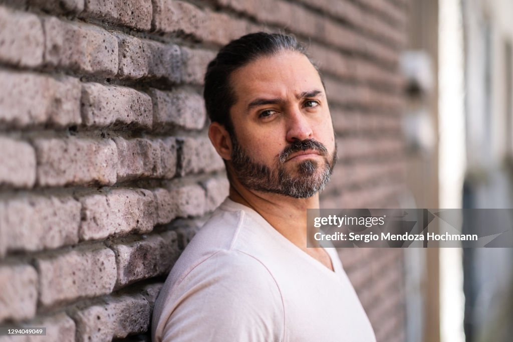 Man standing against a grey and purple brick wall looking at the camera
