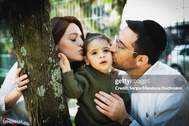 a young jewish family kissing their young boy - jew cap stock pictures, royalty-free photos & images