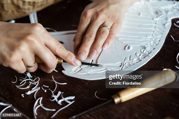 female hands cutting a stamp from a plastic blank with a special cutter for prints of linocut on paper - linocut stock pictures, royalty-free photos & images