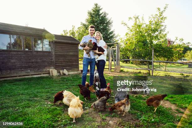 outdoor portrait of young couple with chickens and goat - couple farm stock pictures, royalty-free photos & images