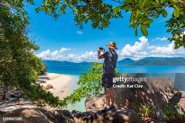 tourist taking photo of nudey beach, fitzroy island national park, australia - cairns australië stockfoto's en -beelden