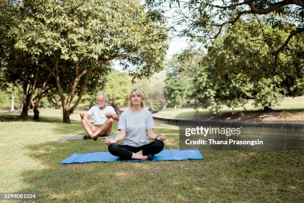 mature couple doing yoga at the park - matching outfits stock pictures, royalty-free photos & images