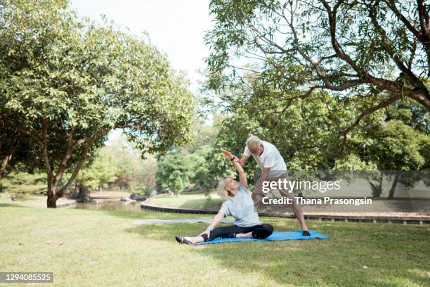 senior couple stretching together outdoors. - senior yoga stock-fotos und bilder