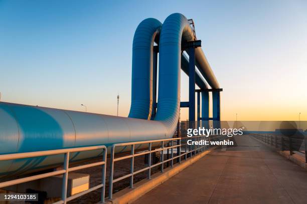 blue pipes going to oil refinery - oil gas stock-fotos und bilder