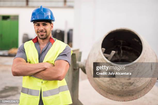 bauarbeiter posiert während einer gebäudesanierung gerne neben einem betonmischer. starker mann porträt - betonmischer stock-fotos und bilder