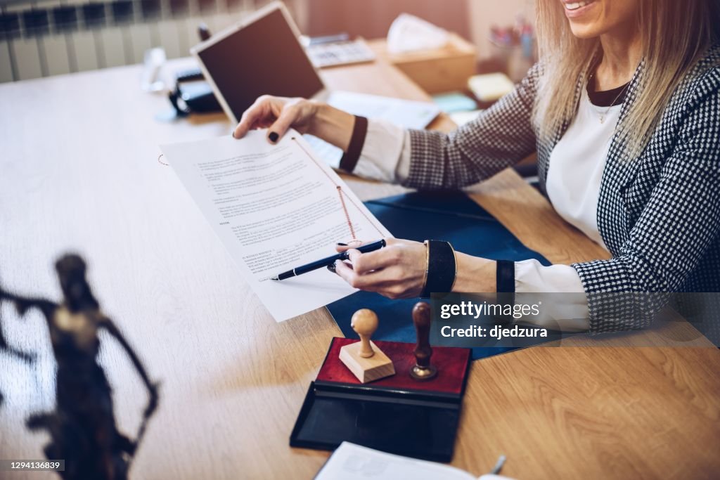 Frau Notar öffentliche halten Stift und zeigt auf Unterschrift Ort.