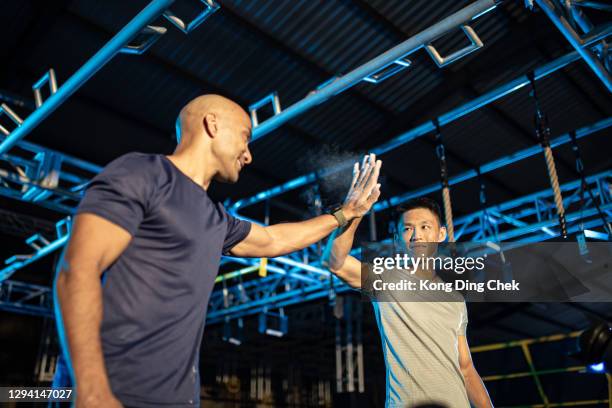 asiatische multi-ethik-männer high five bereiten sich auf das training eines hindernisparcours vor. - assault courses stock-fotos und bilder