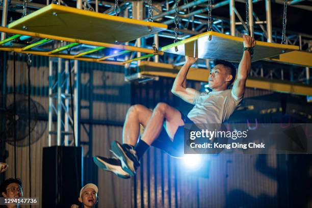 asian chinese man athlete competing in an obstacle course. team member encourage and cheering with him. - assault courses stock pictures, royalty-free photos & images